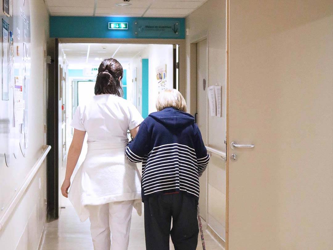Une Résidente au bras d'une soignante